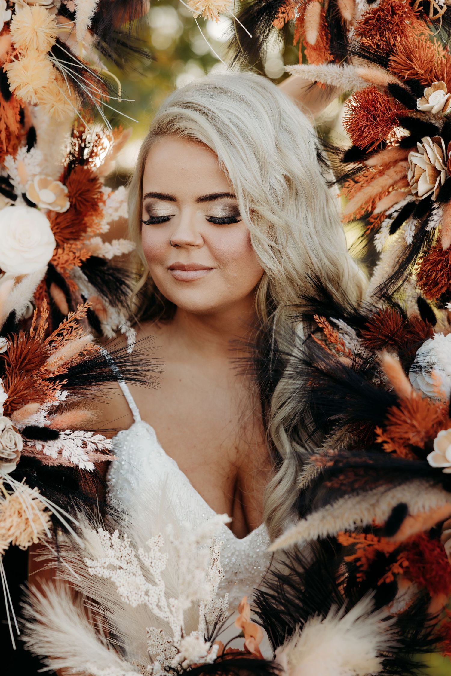 Blonde bride surrounded by boho dried floral arrangement with rust and cream tones in a dreamy double exposure portrait.