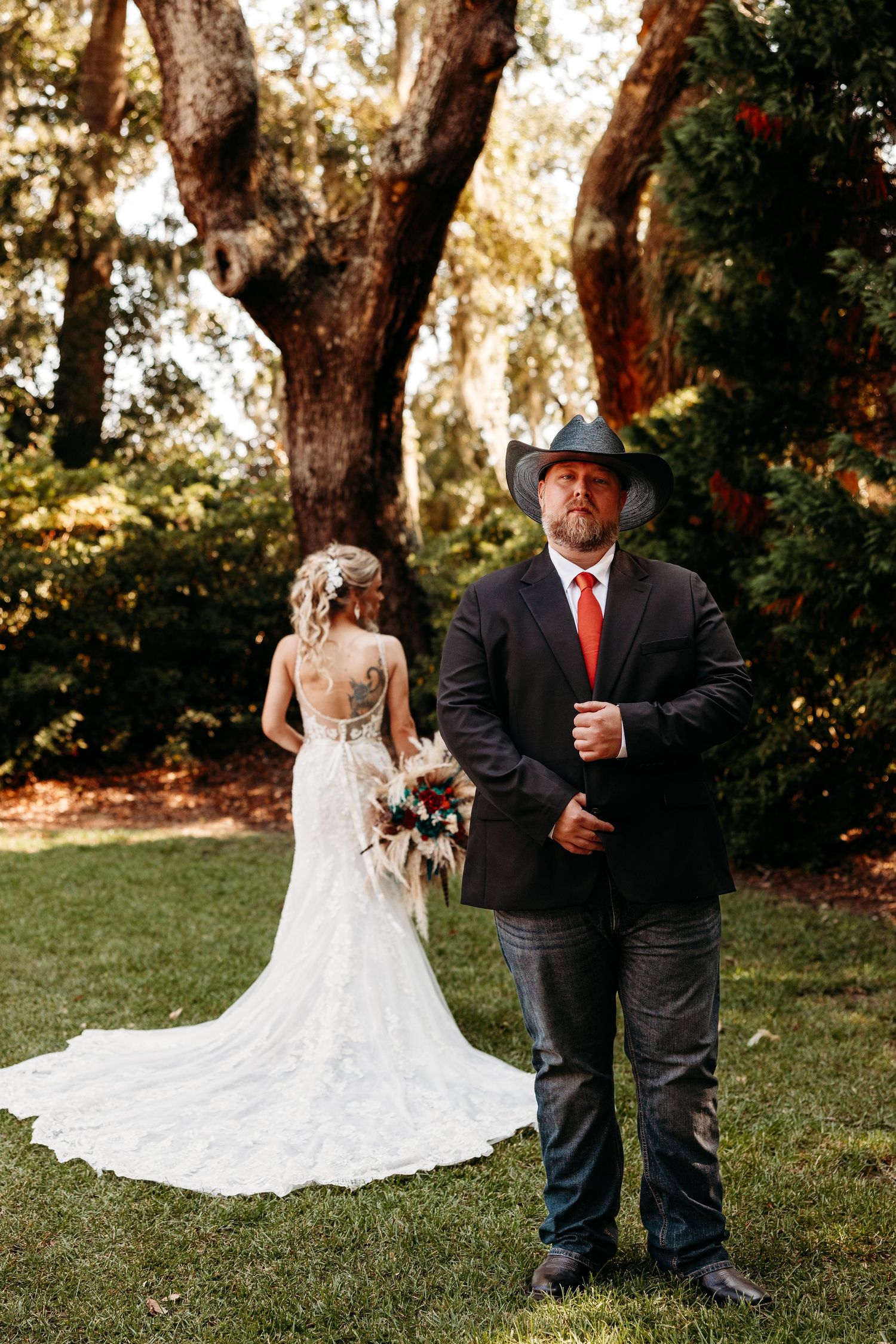 A wedding couple poses in a garden setting with beautiful greenery and trees.