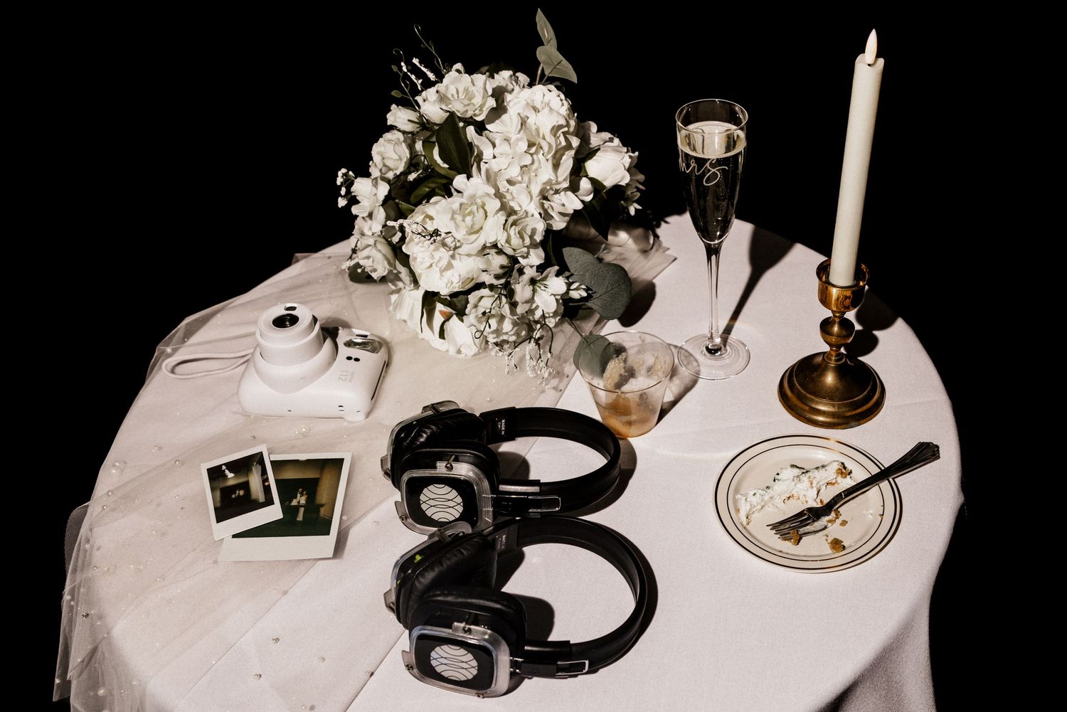 End of night wedding reception table set with white flowers, candles and elegant place settings.