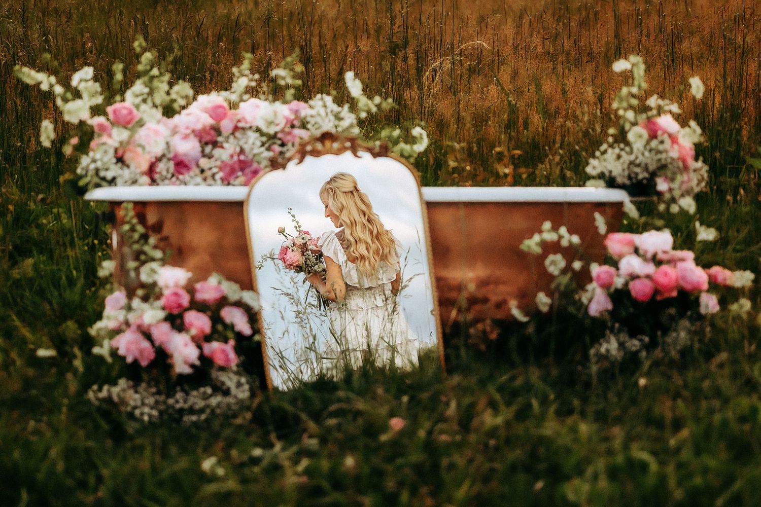 Vintage white furniture decorated with pink roses arranged in a rustic field setting.