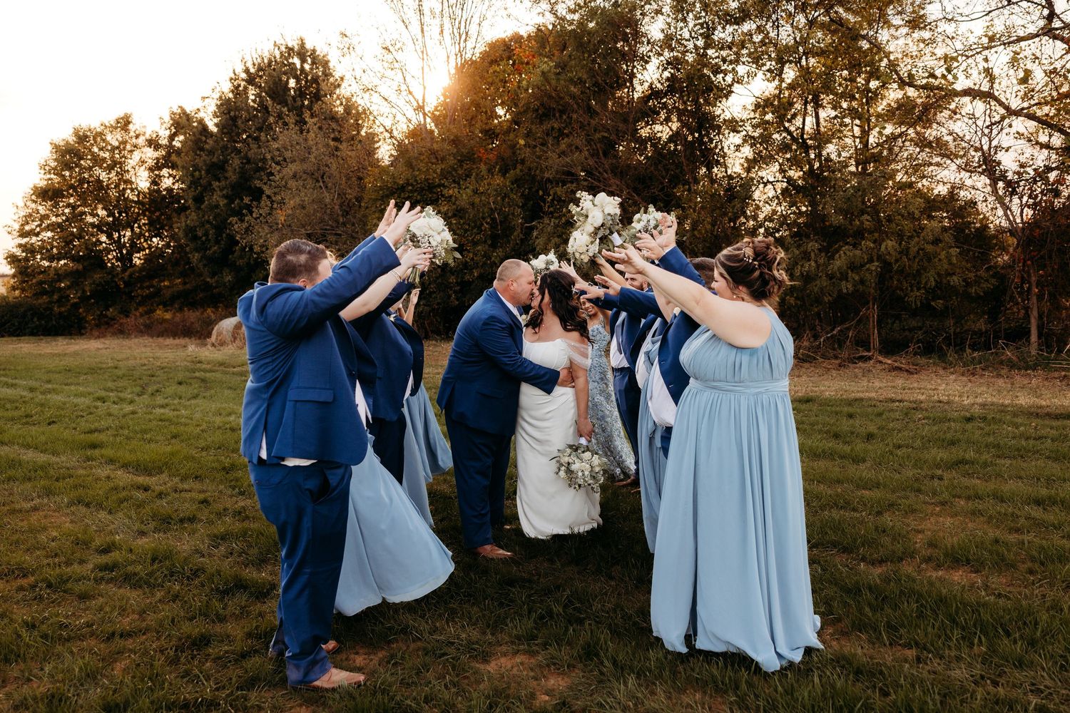 Wedding party celebrates outdoors with champagne toast at sunset.