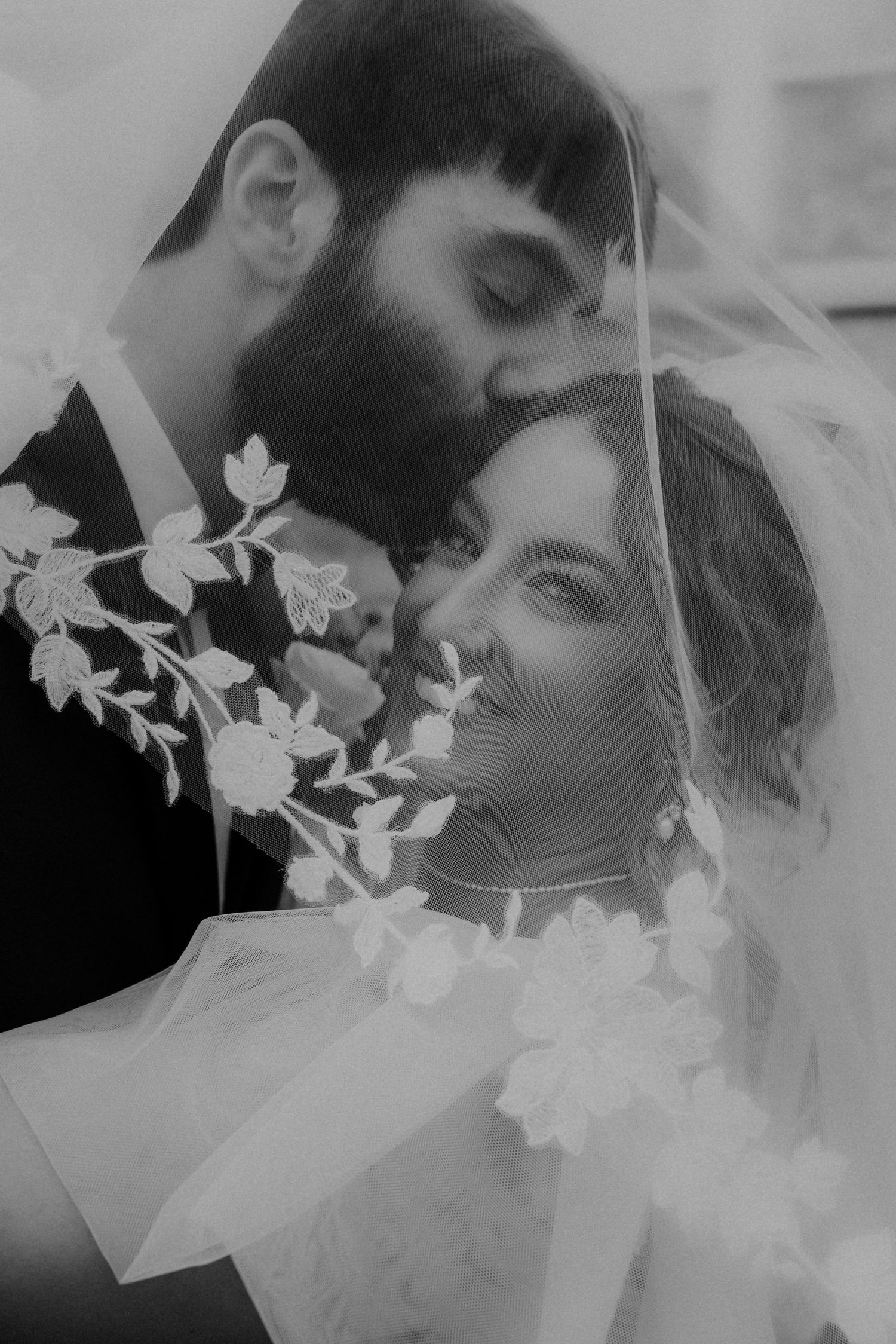 An intimate black and white wedding portrait with delicate floral details and veil.