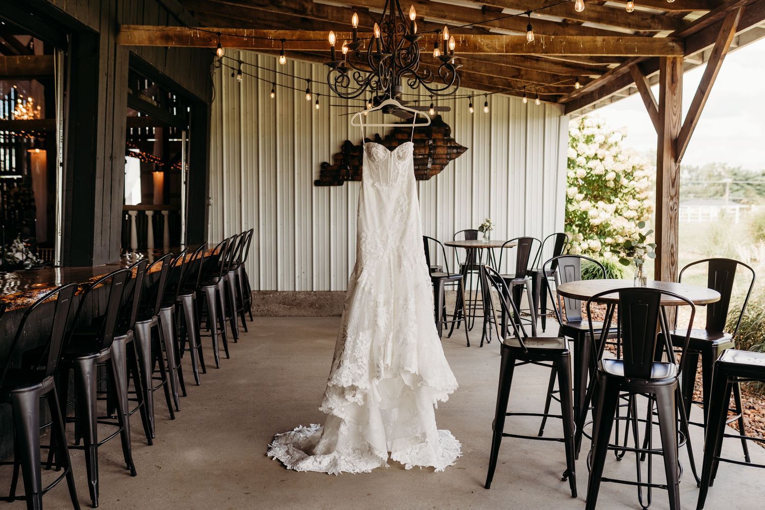 An elegant rustic barn wedding venue with hanging lights and black chairs.