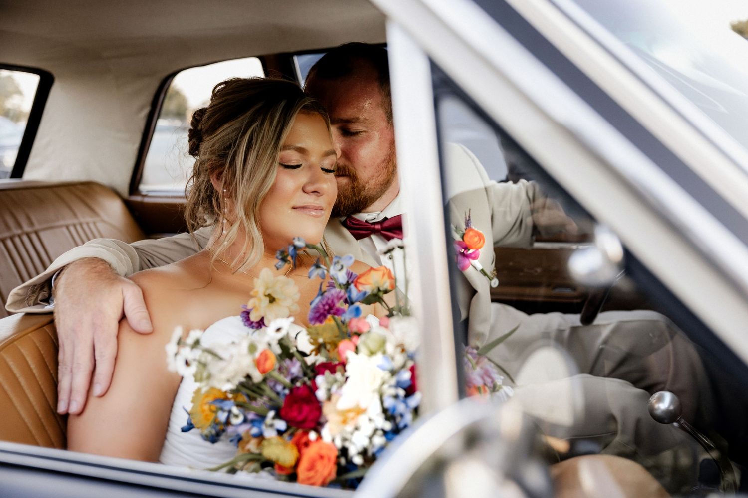 Colorful wildflower bouquet held inside a classic car at Phillips Grove wedding venue.