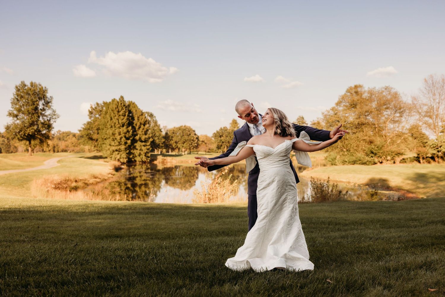 Wedding couple dancing in an open field at sunset.