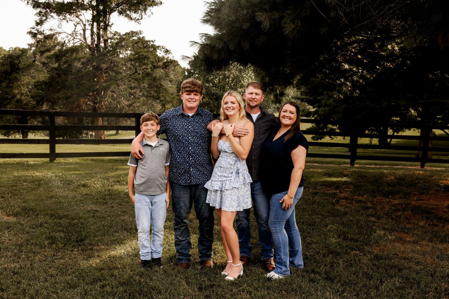 Family group photo session in a park setting with trees in the background.