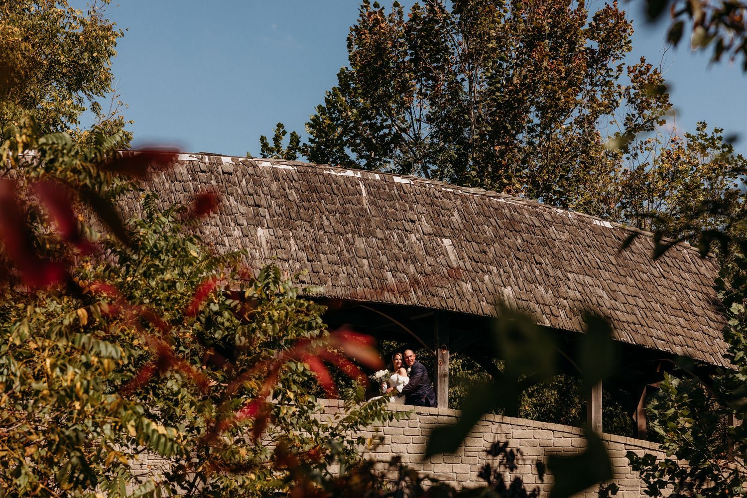 Scenic outdoor wedding venue with stone pillars and wooden beams against a blue sky.