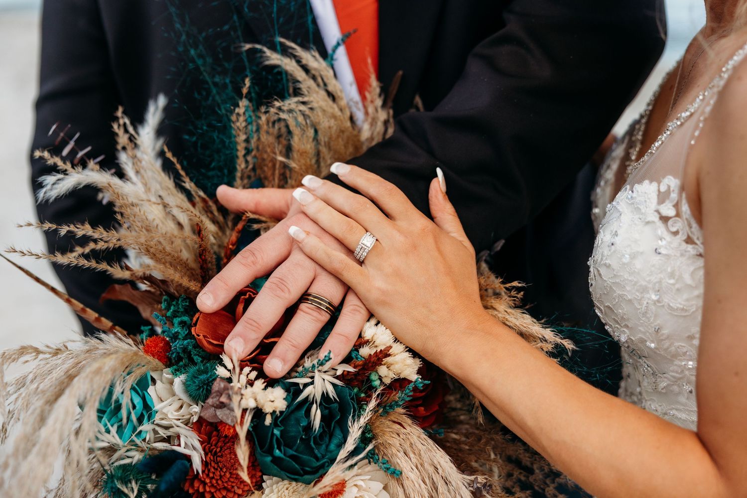 Close-up details of wedding rings and hands with turquoise accents.