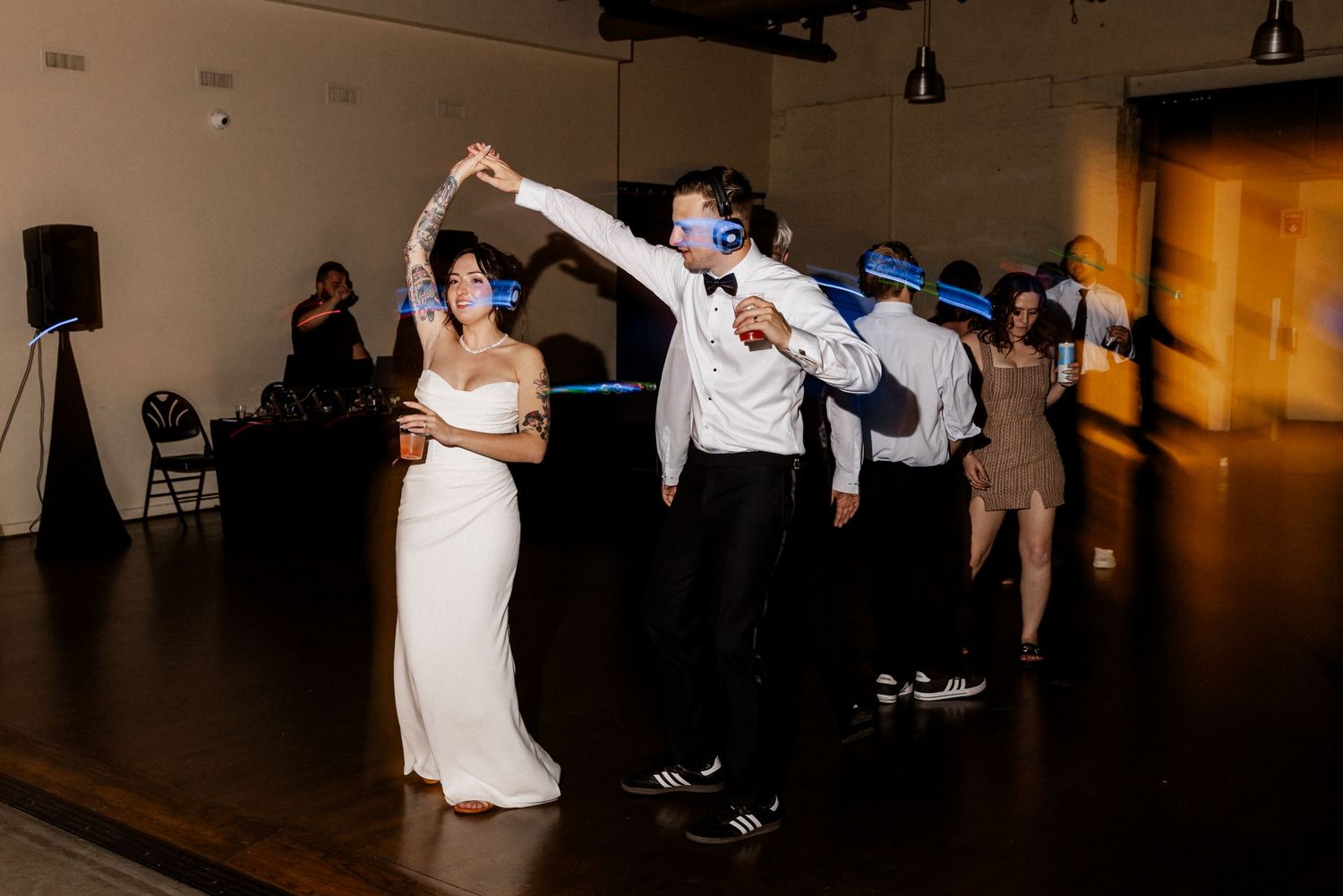 Wedding guests dancing at silent disco wedding reception in dimly lit venue.