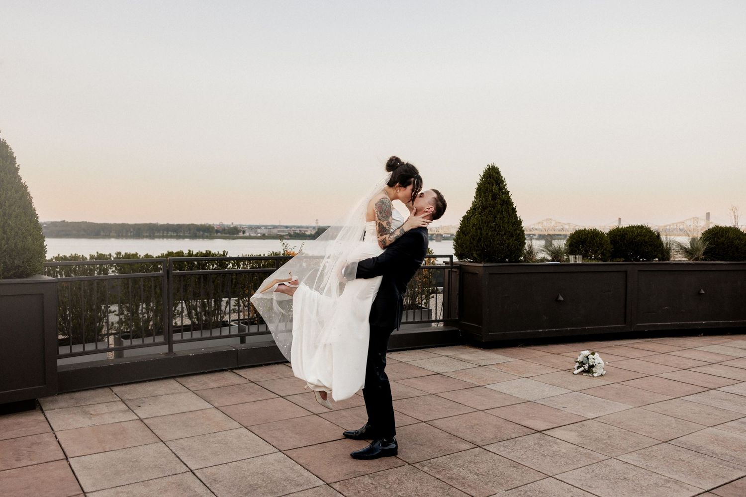Wedding couple shares a romantic moment on a rooftop terrace at sunset overlooking the Louisville city skyline.