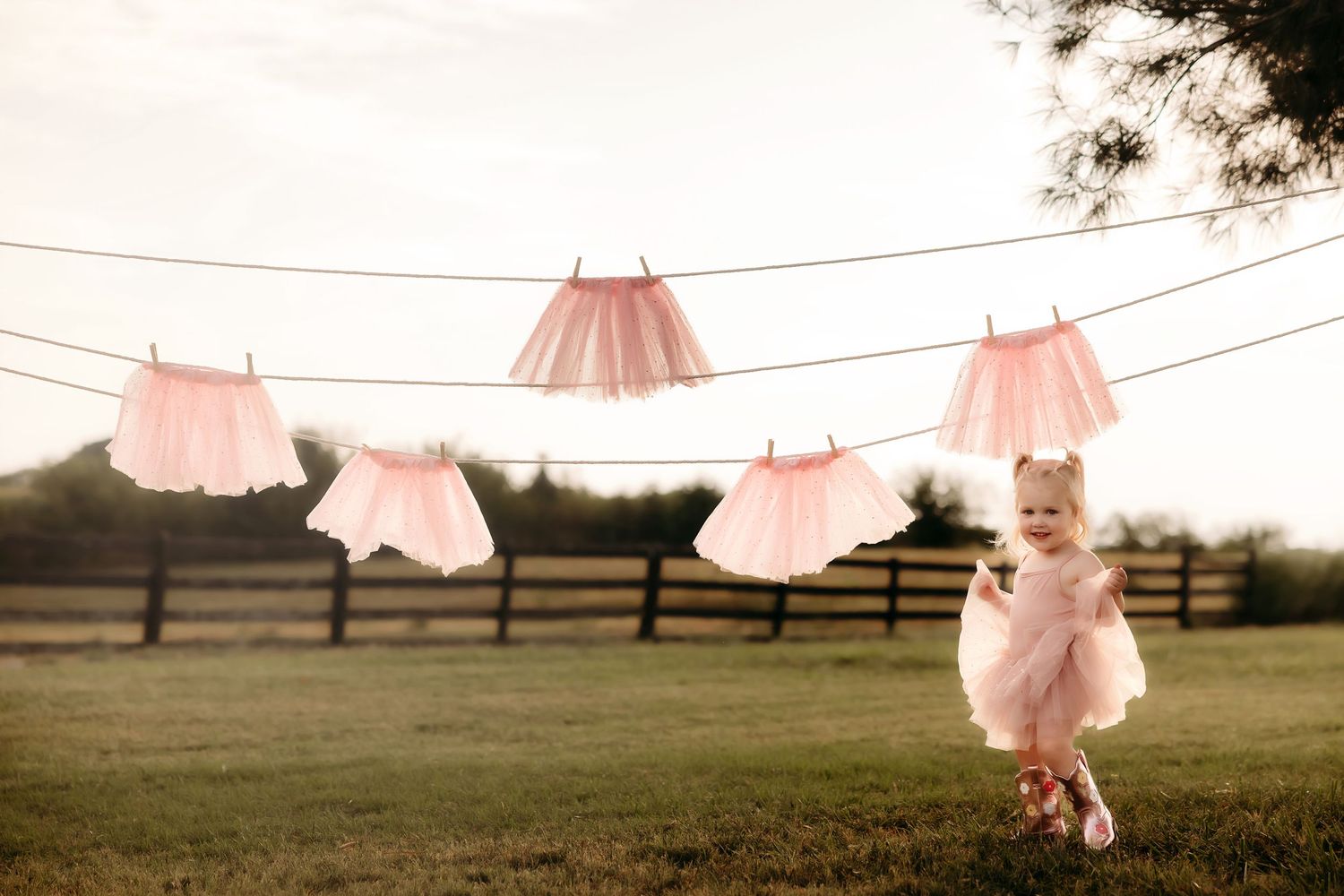 Pink tutus hang on a clothesline while a small figure dances in a matching outfit.