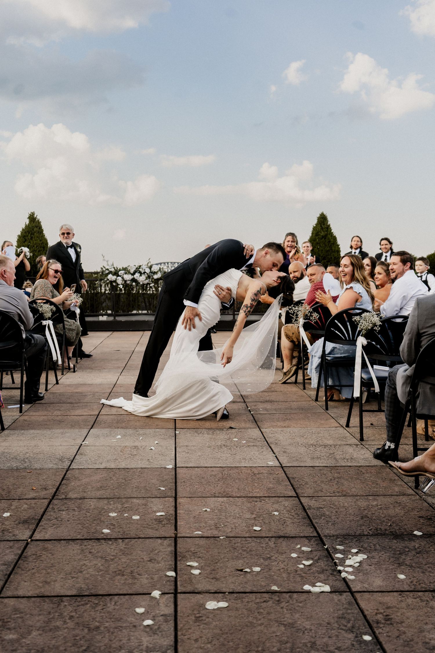 Dramatic dip kiss between newlyweds during outdoor wedding ceremony with seated guests at Frazier History Museum wedding venue in Louisville