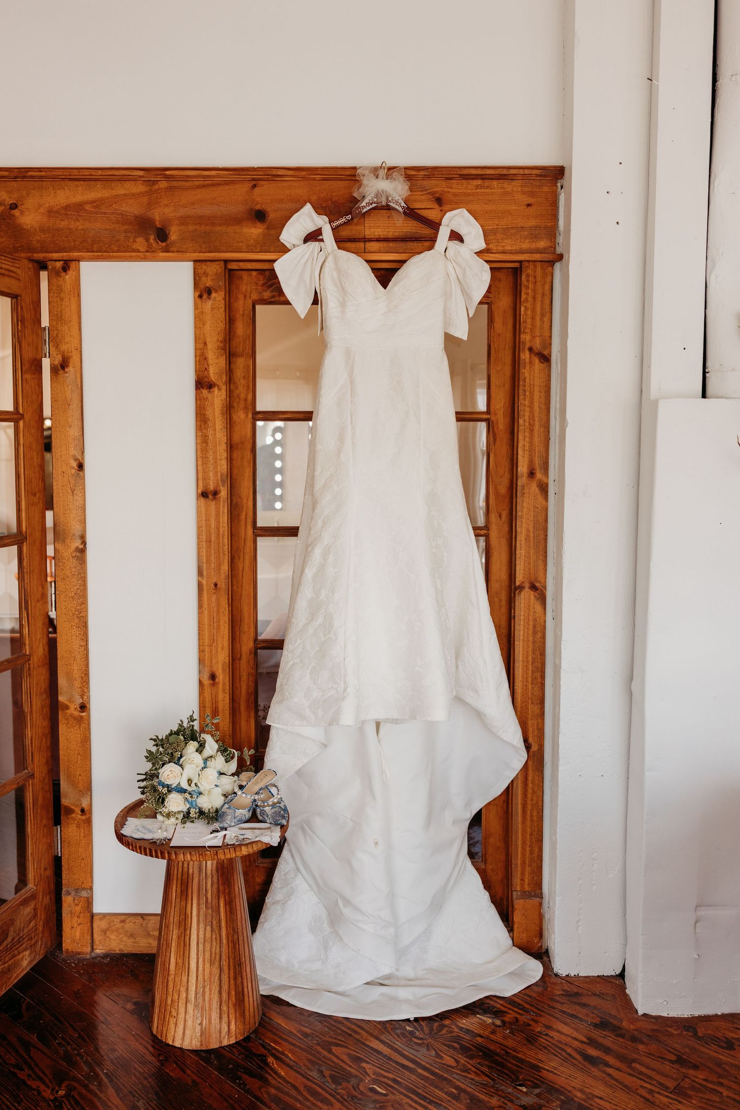 White wedding dress displayed against rustic wooden doorframes.