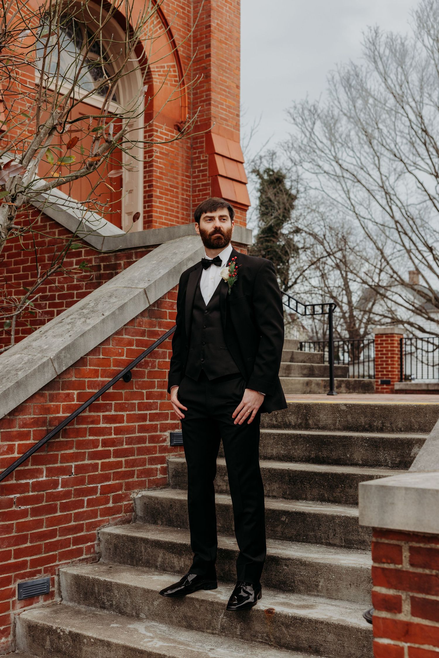 A person in formal attire sits on brick steps outside a building.