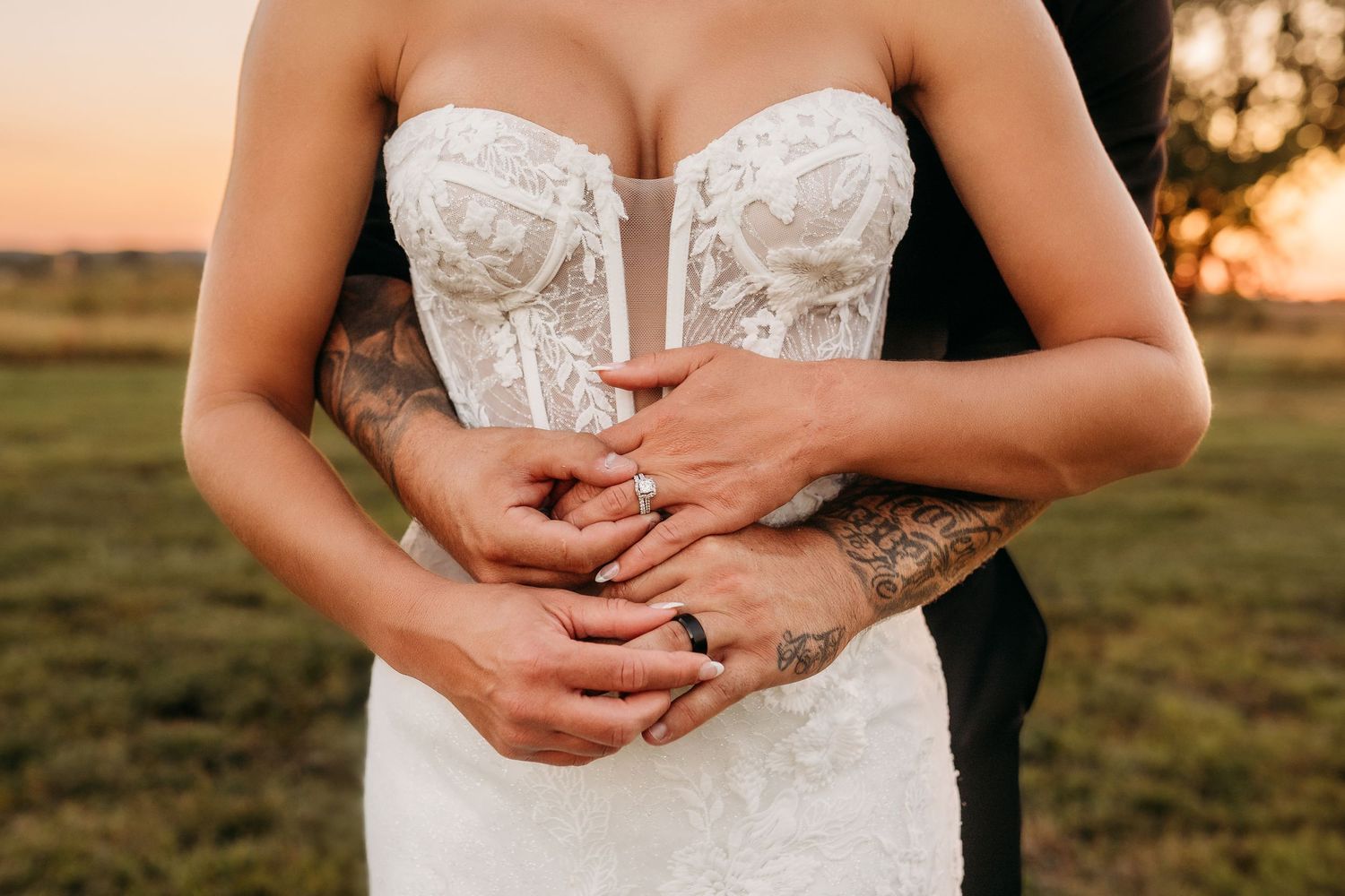 Close-up details of a white lace wedding dress bodice against sunset lighting.