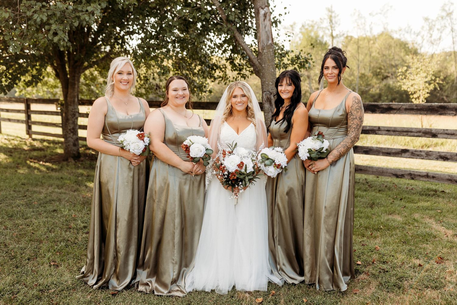 Wedding party in gray dresses posing together outdoors with bouquets at Cornerstone Acres.
