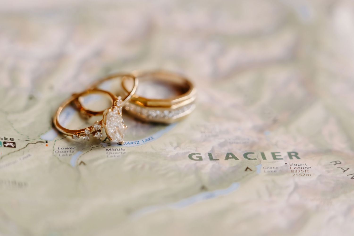 Gold wedding rings resting on a Glacier National Park map, symbolizing adventure and love.