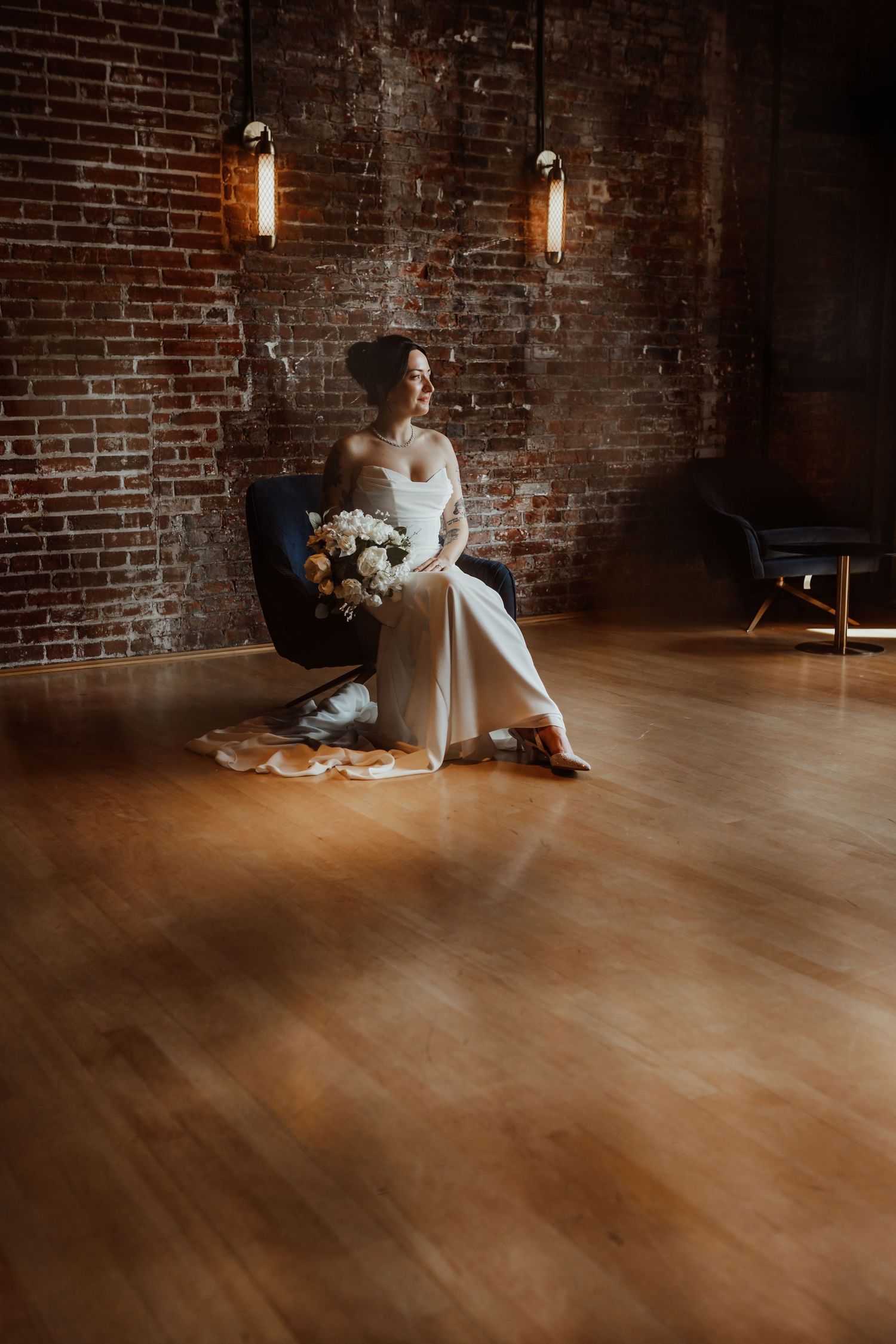 Industrial wedding venue interior featuring exposed brick walls, wooden floors, and dramatic lighting.