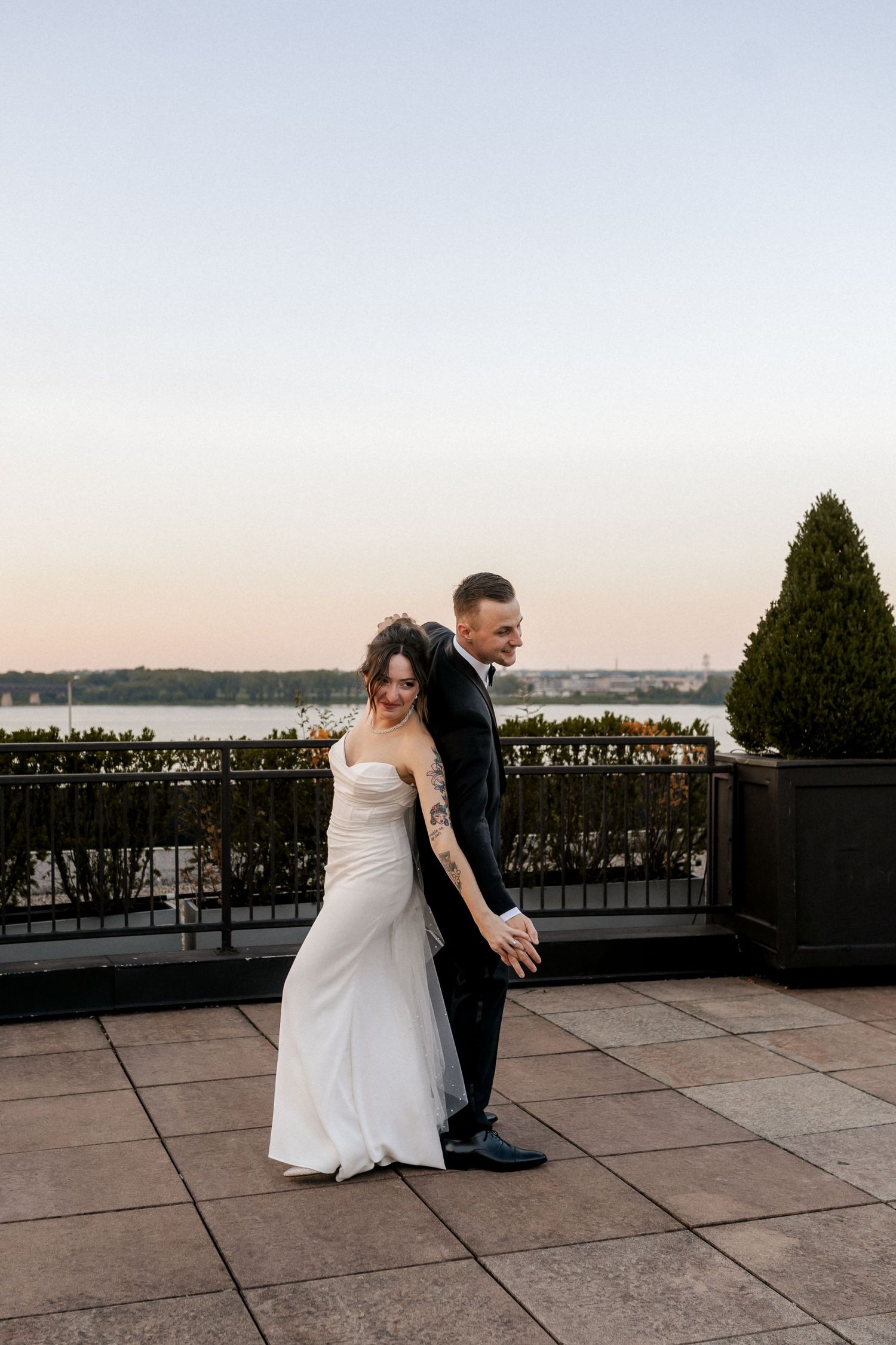 Romantic sunset portrait of newlyweds on outdoor terrace with Louisville waterfront view.