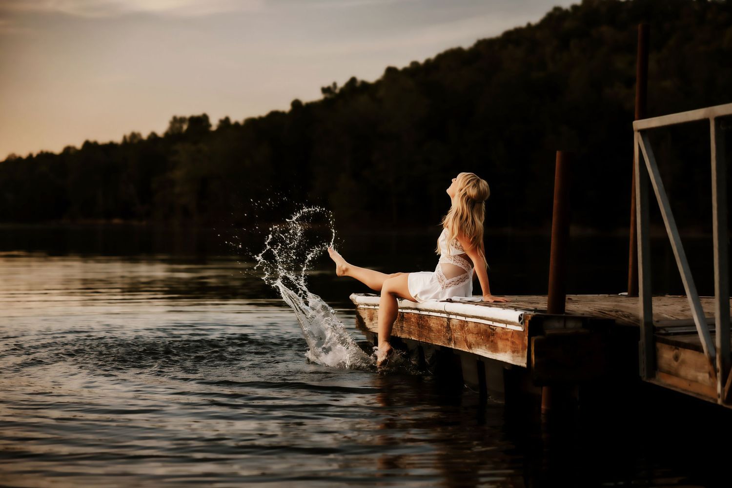 Water splashes dramatically on wooden dock during sunset photoshoot.