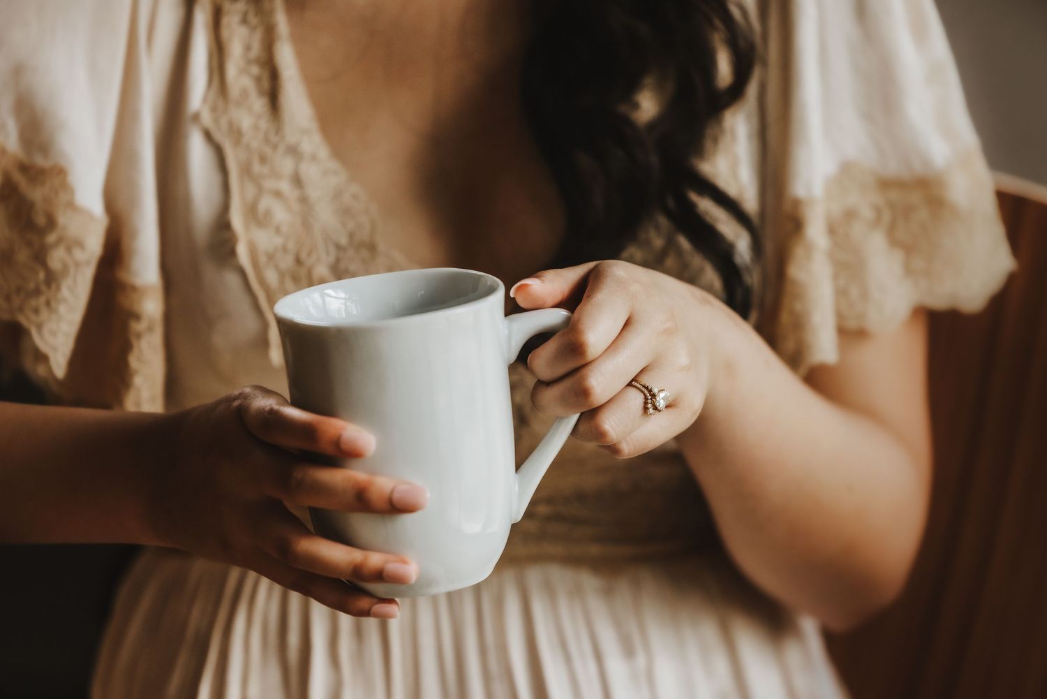 Close-up of delicate lace details and teacups in warm indoor lighting.