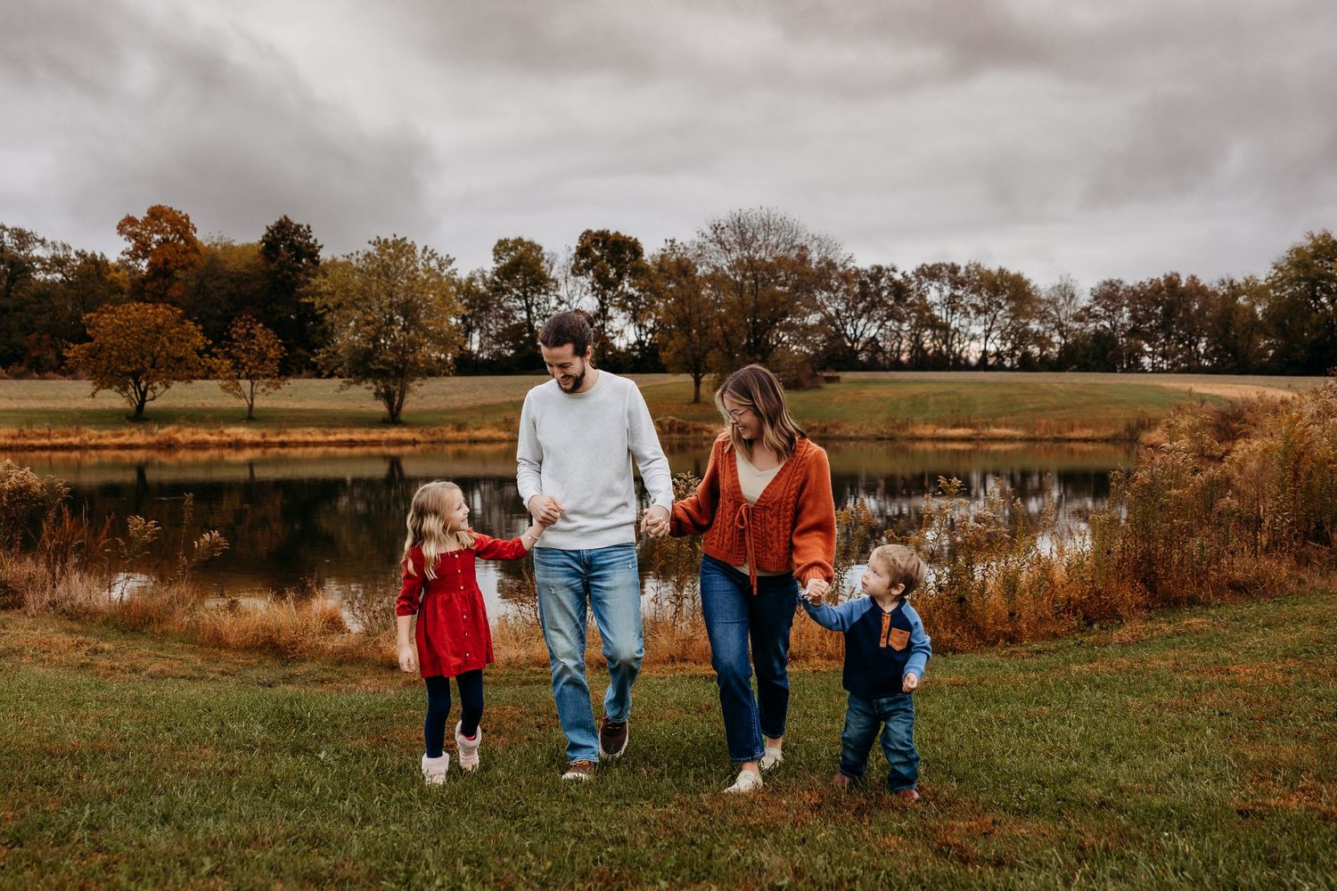 Family walking together through autumn field during golden hour sunset.