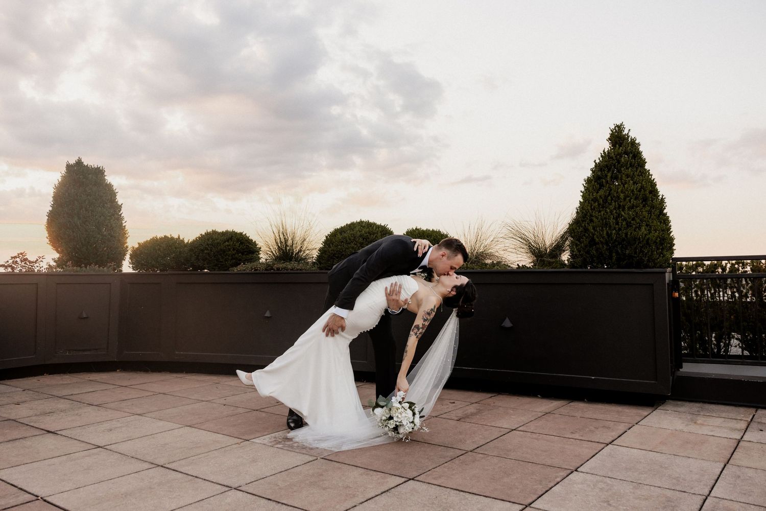 A romantic dip pose on an outdoor terrace during a wedding photoshoot.