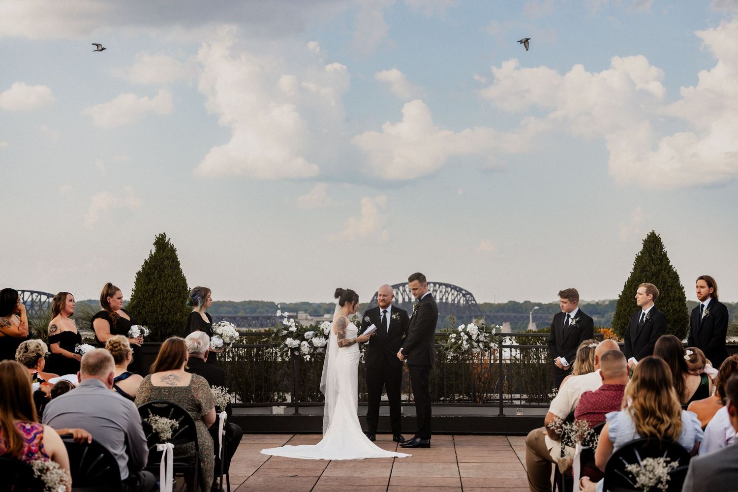 Outdoor rooftop wedding ceremony with Louisville cityscape and bridge views in background.