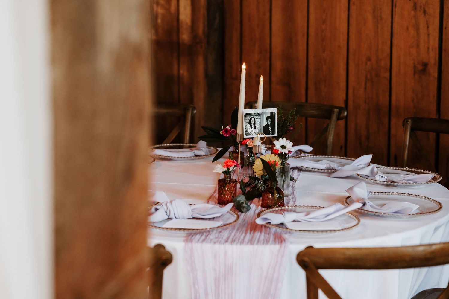 Elegant table settings with white linens and floral centerpieces in a rustic wooden barn at The Warrenwood Manor.