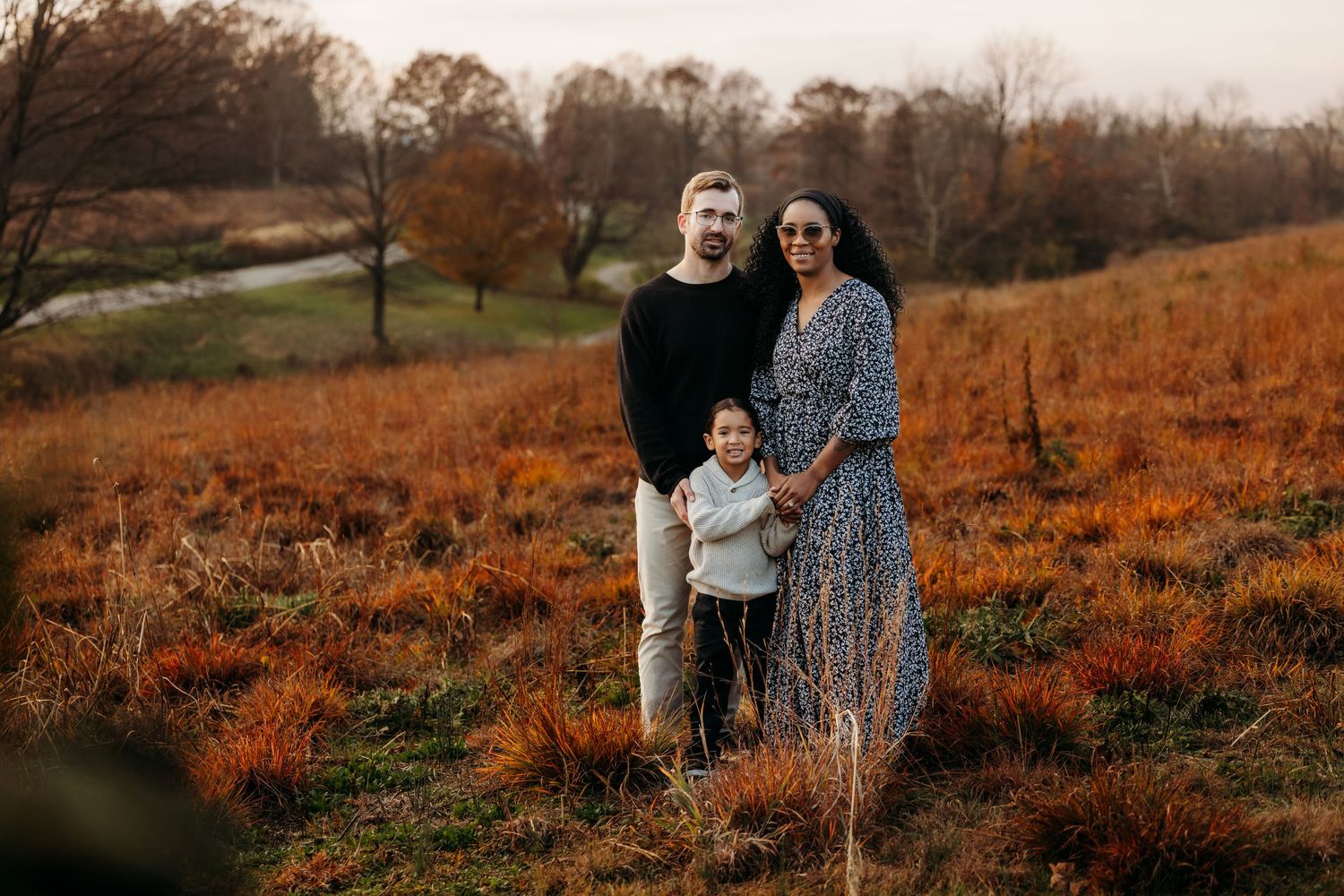 Candid family photos captured in rustic field with warm fall colors at dusk.