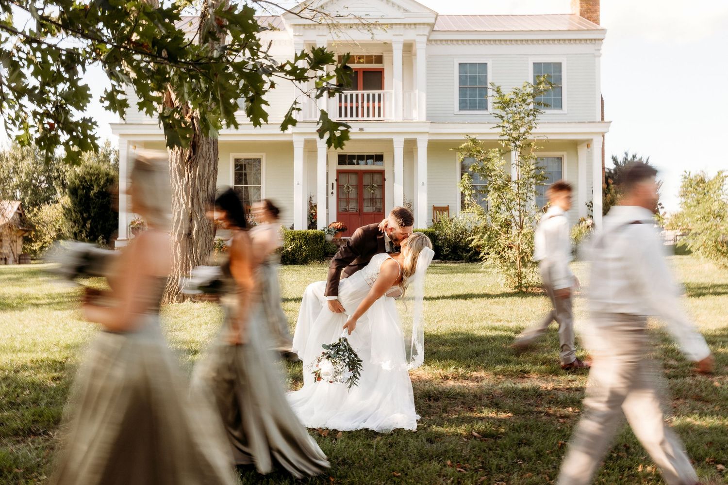 Wedding party running and celebrating outside a classic white colonial-style house in Springfield, KY.