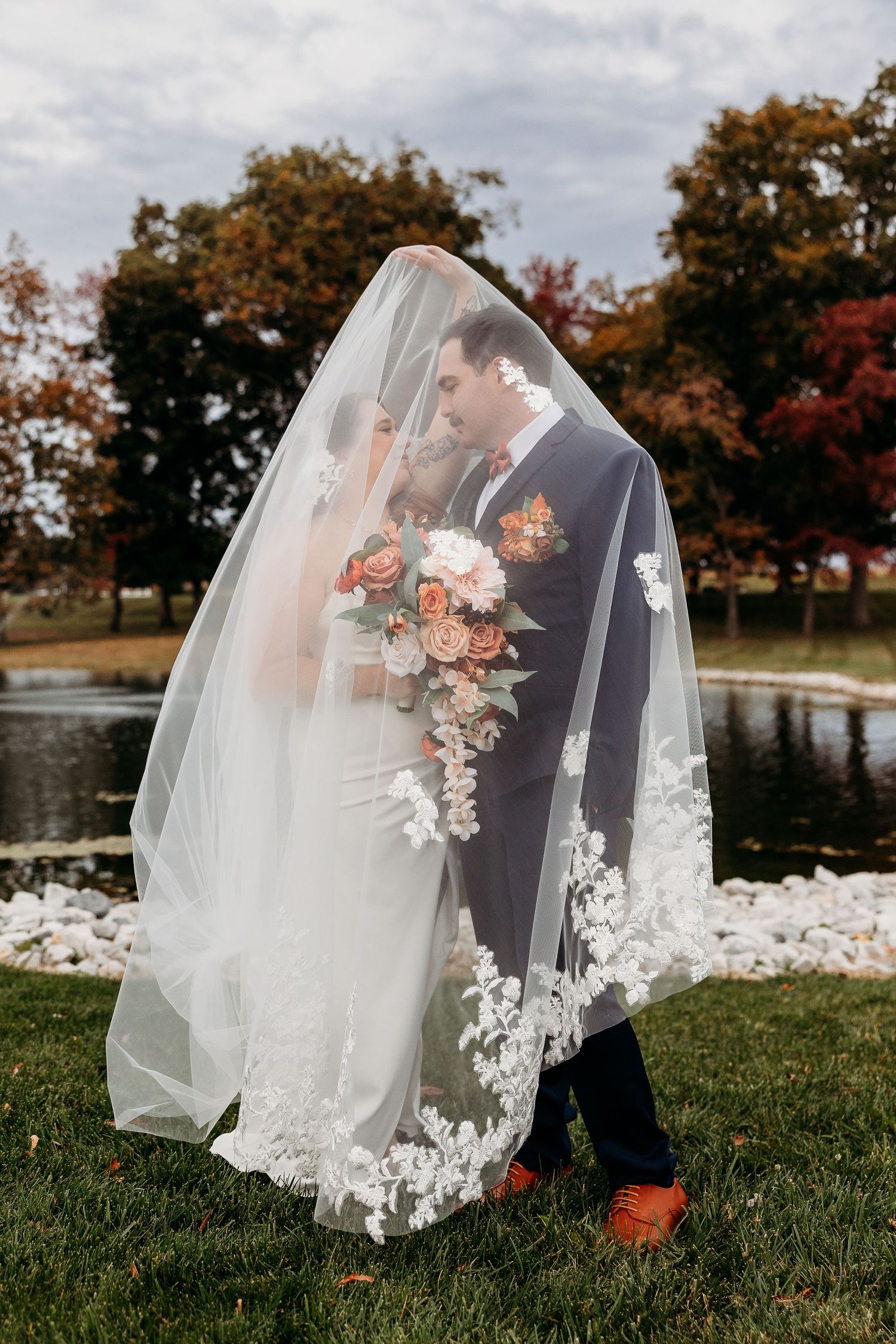 Wedding veil detail shots on grass with delicate lace and floral embellishments.