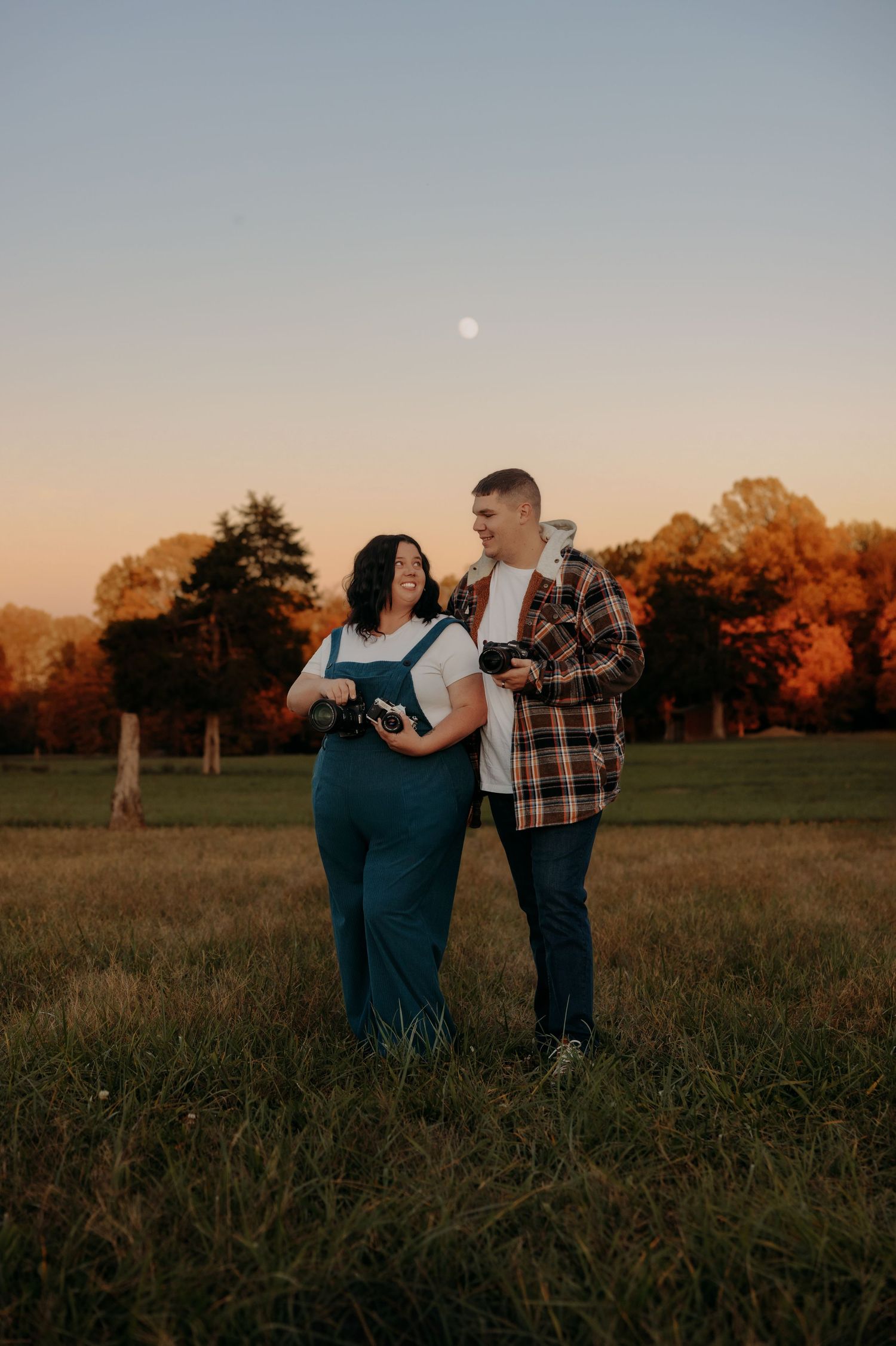 Sunset photoshoot in an open field with warm autumn colors in the background.