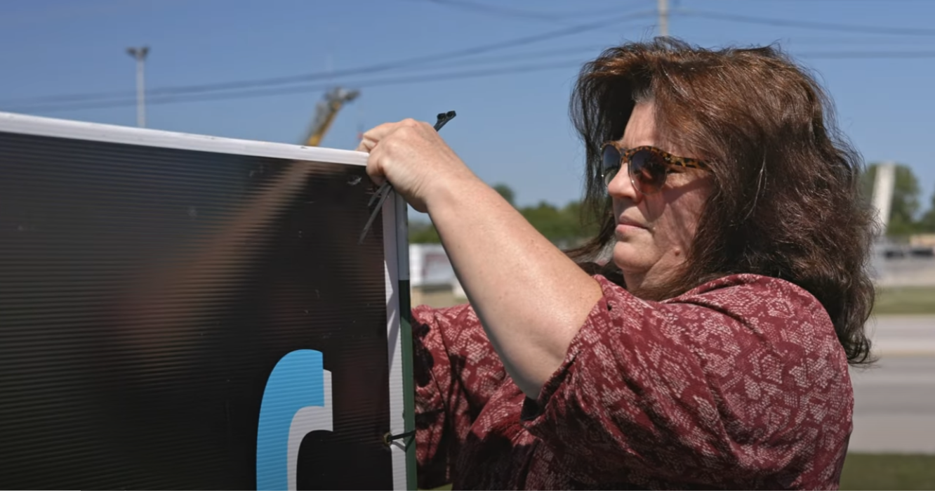 Someone reaching up to adjust equipment on a black truck exterior.