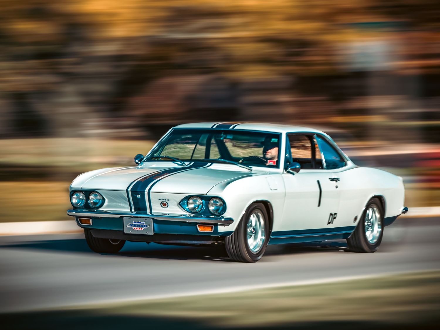 White vintage sports car in motion with motion blur effect on a curved road.