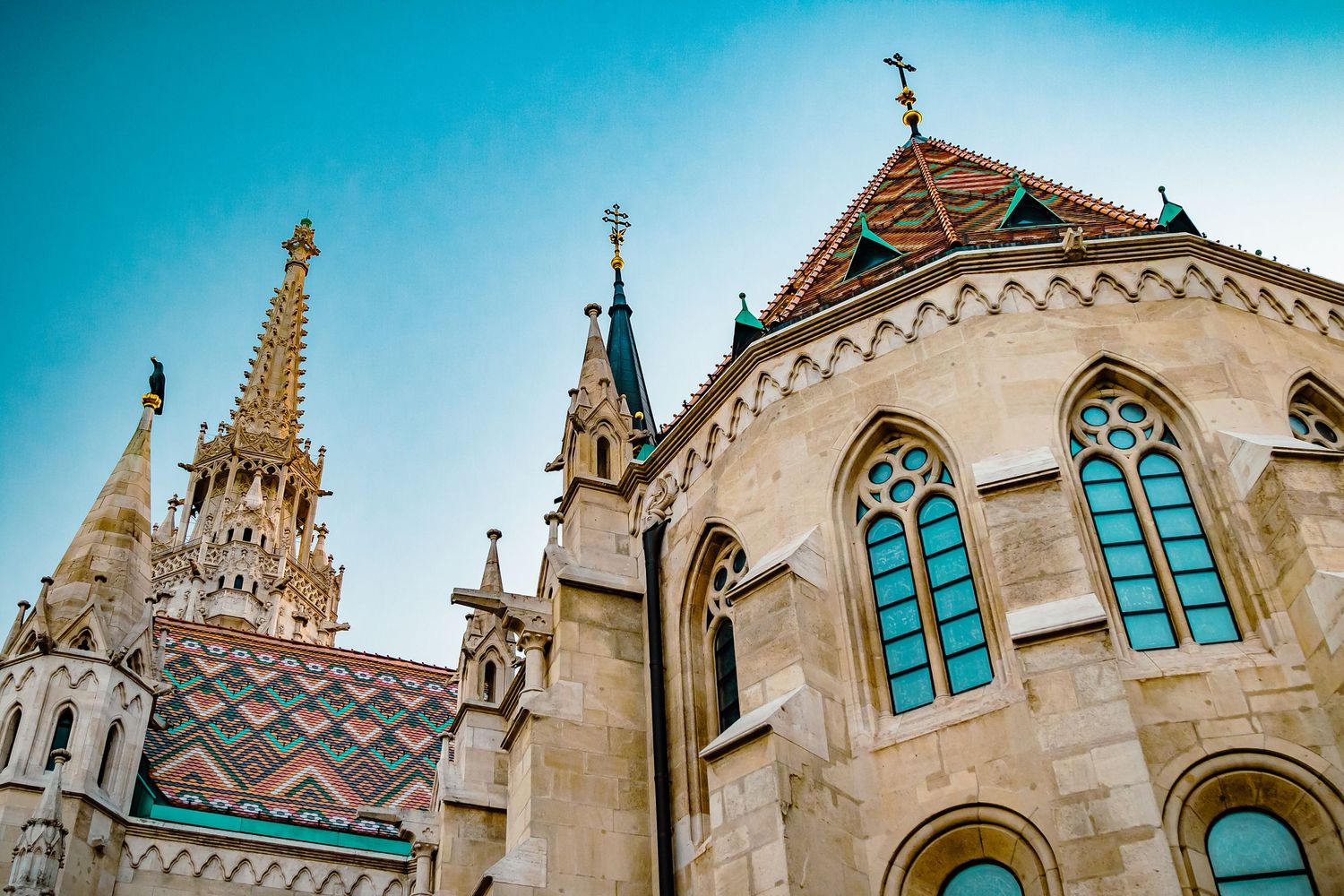 Gothic cathedral spires and arched windows against bright blue sky with ornate architectural details and patterns.