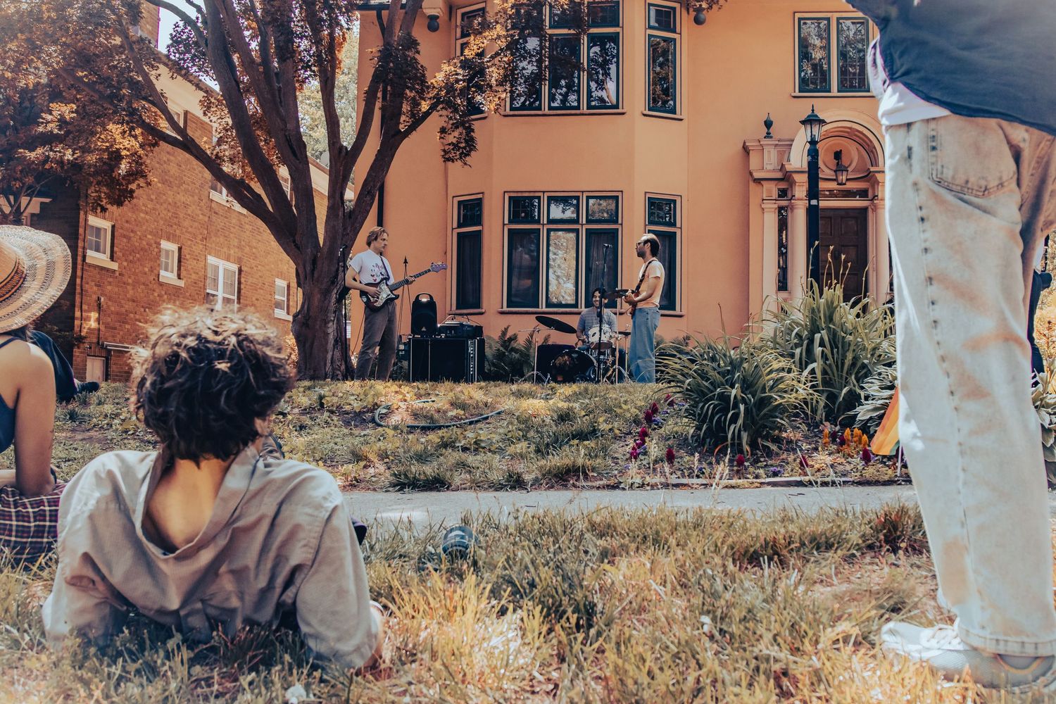 Person relaxing on grass near orange building with urban architecture in background.
