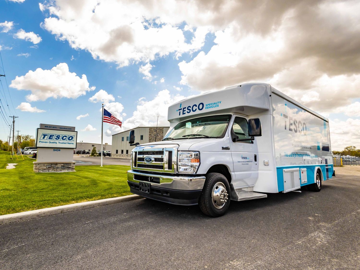 White Tesco delivery truck parked outside company headquarters with flag and signage.
