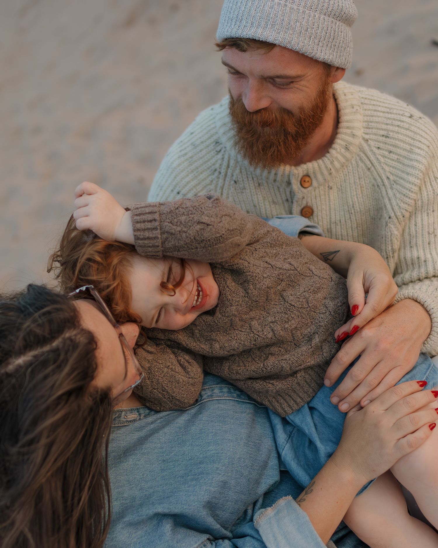 Tender family moment captured in warm lighting with cozy sweaters.