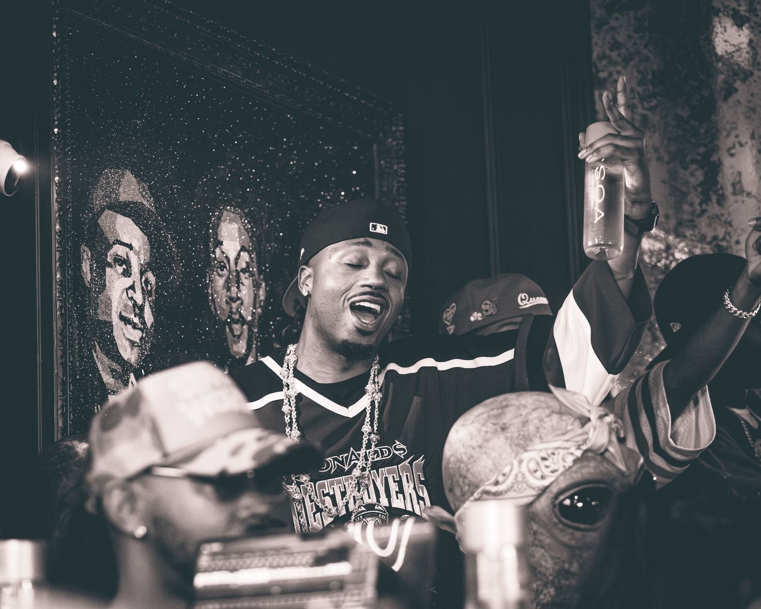 A black and white photo shows people engaged in an energetic performance or gathering in a crowded space.