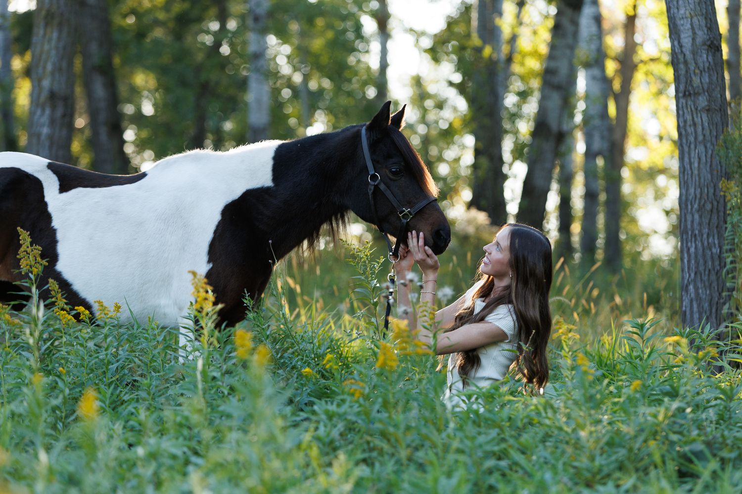 Unedited, cool-toned image of a girl with her pinto pony in the flowers