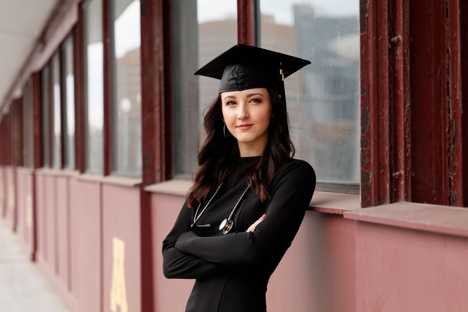 Graduation portraits in black academic regalia against the maroon U of M bridge.