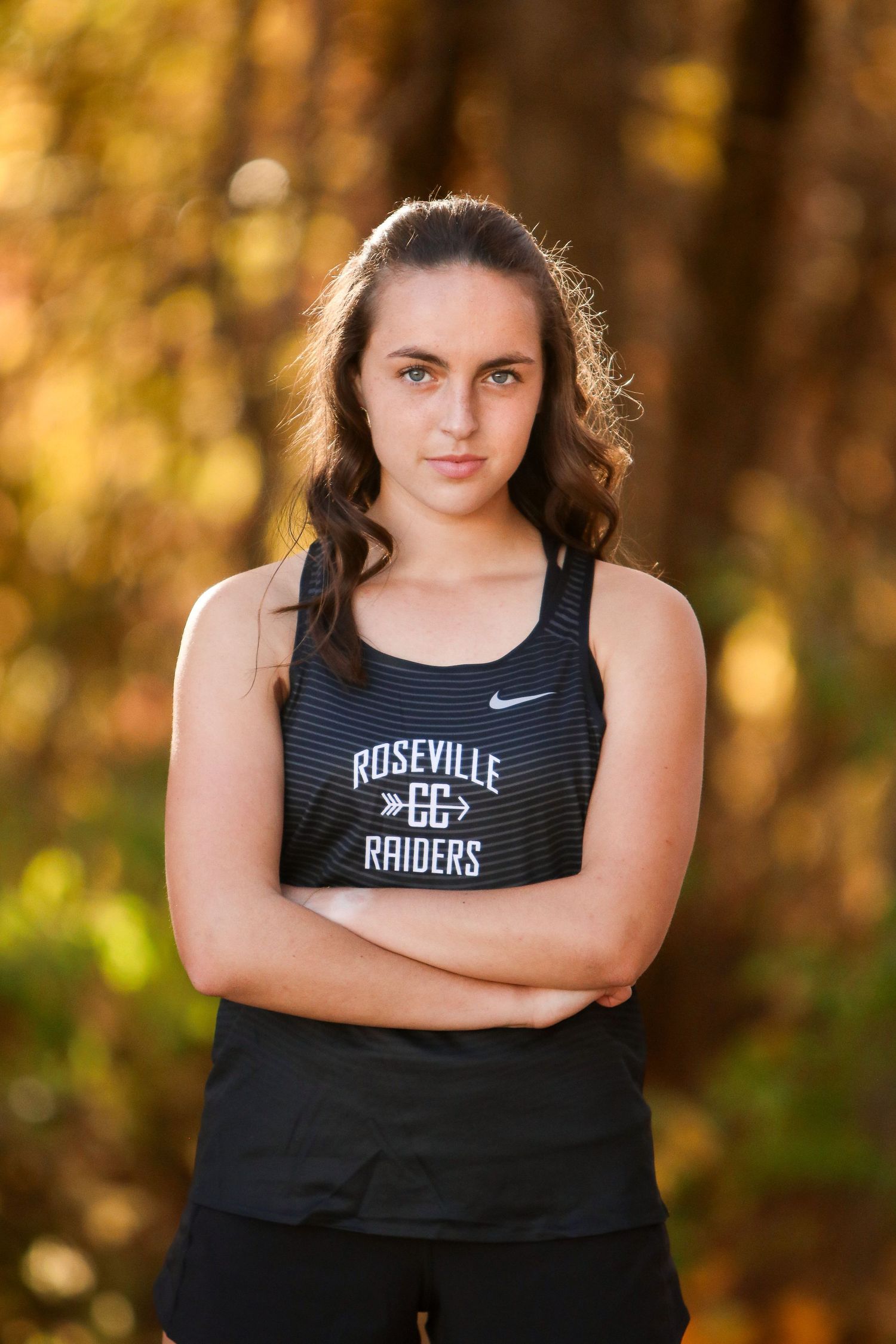 Athletic portrait of a high school senior against autumn foliage.
