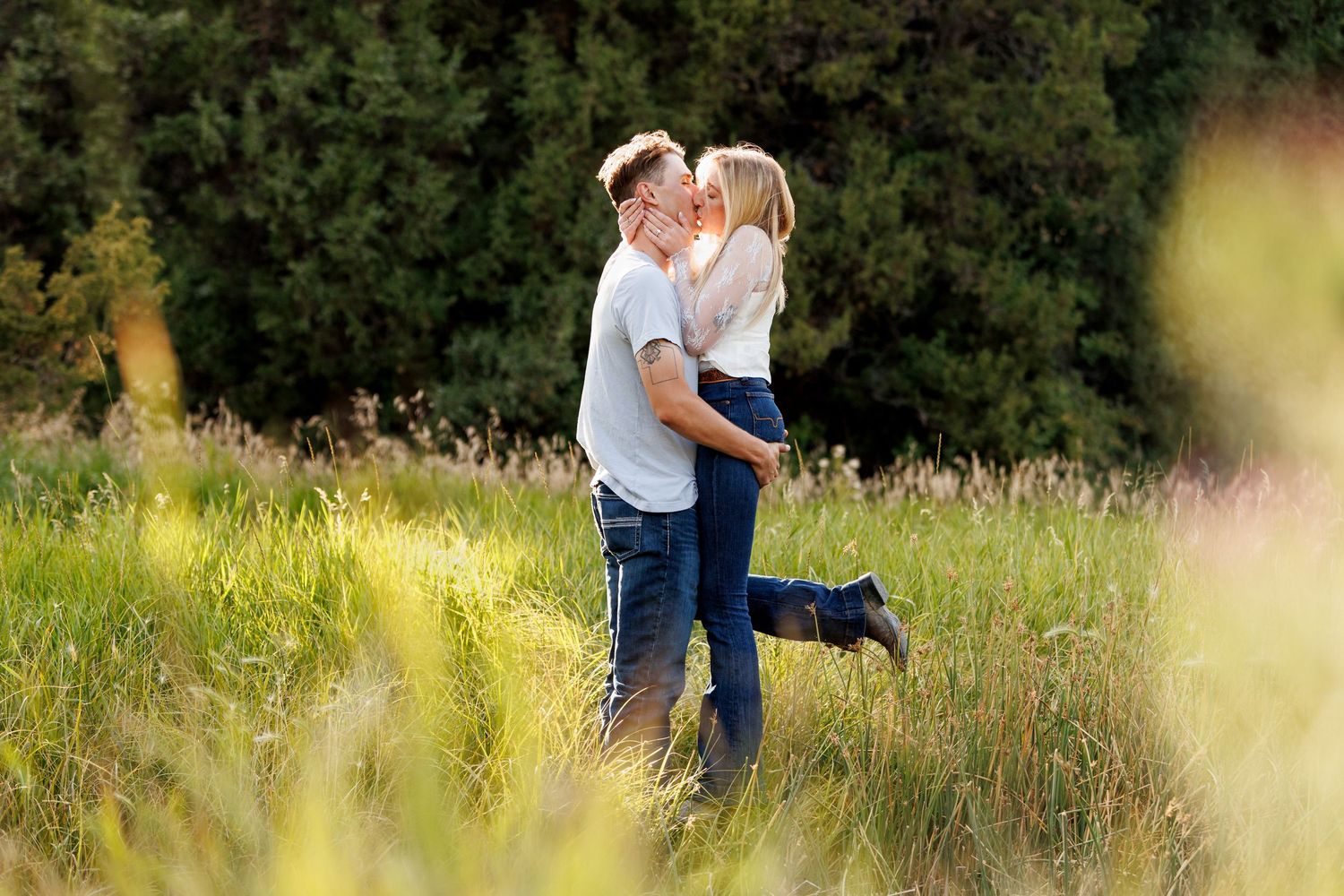 Romantic moment between a couple captured in a sunlit meadow with tall grass.