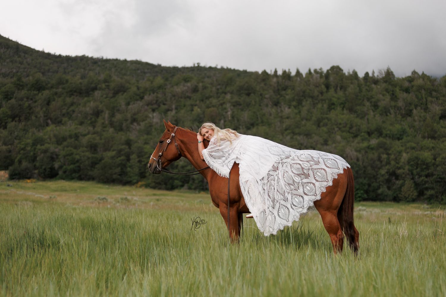 Cowgirl bride laying on her horse in the mountains
