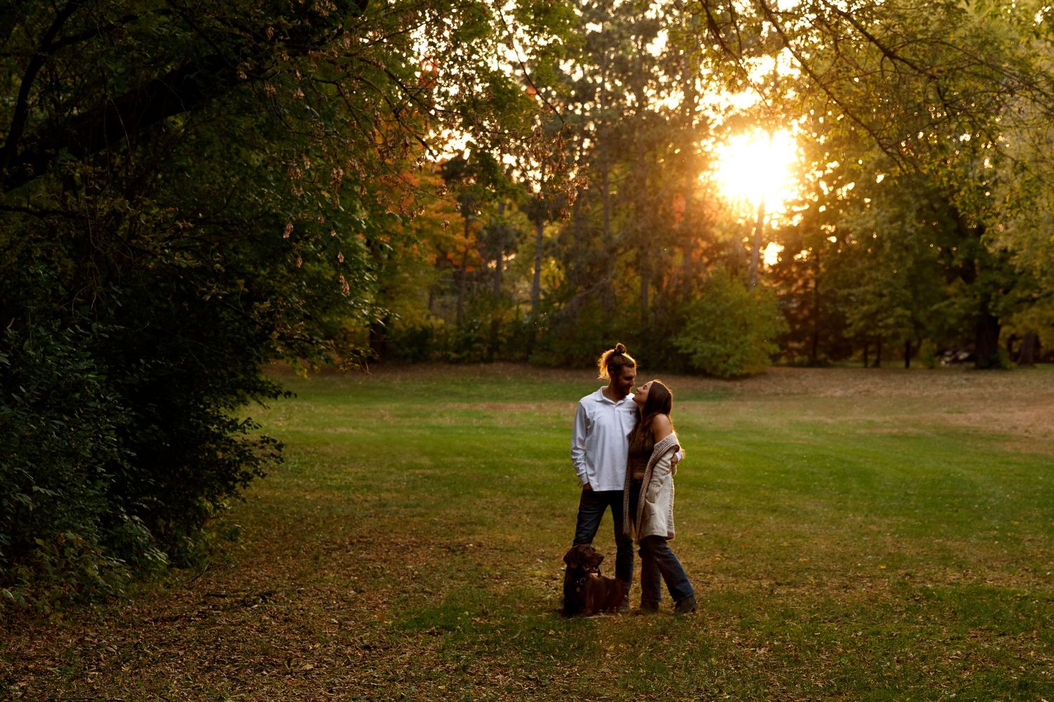 Silhouetted couple standing together in a meadow at sunset.