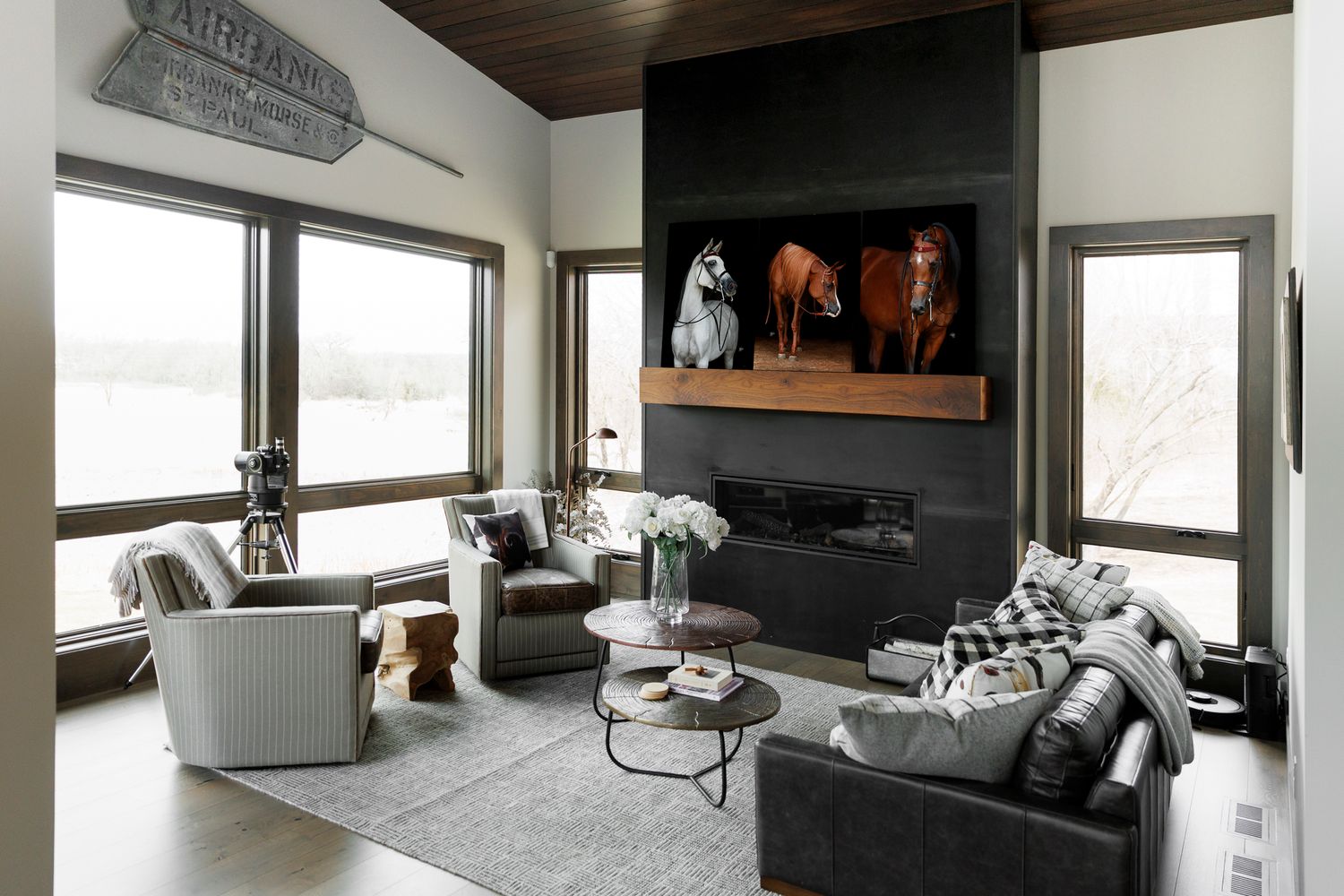 A modern living room that shows three black background prints of stunning horses on the mantle above the fireplace