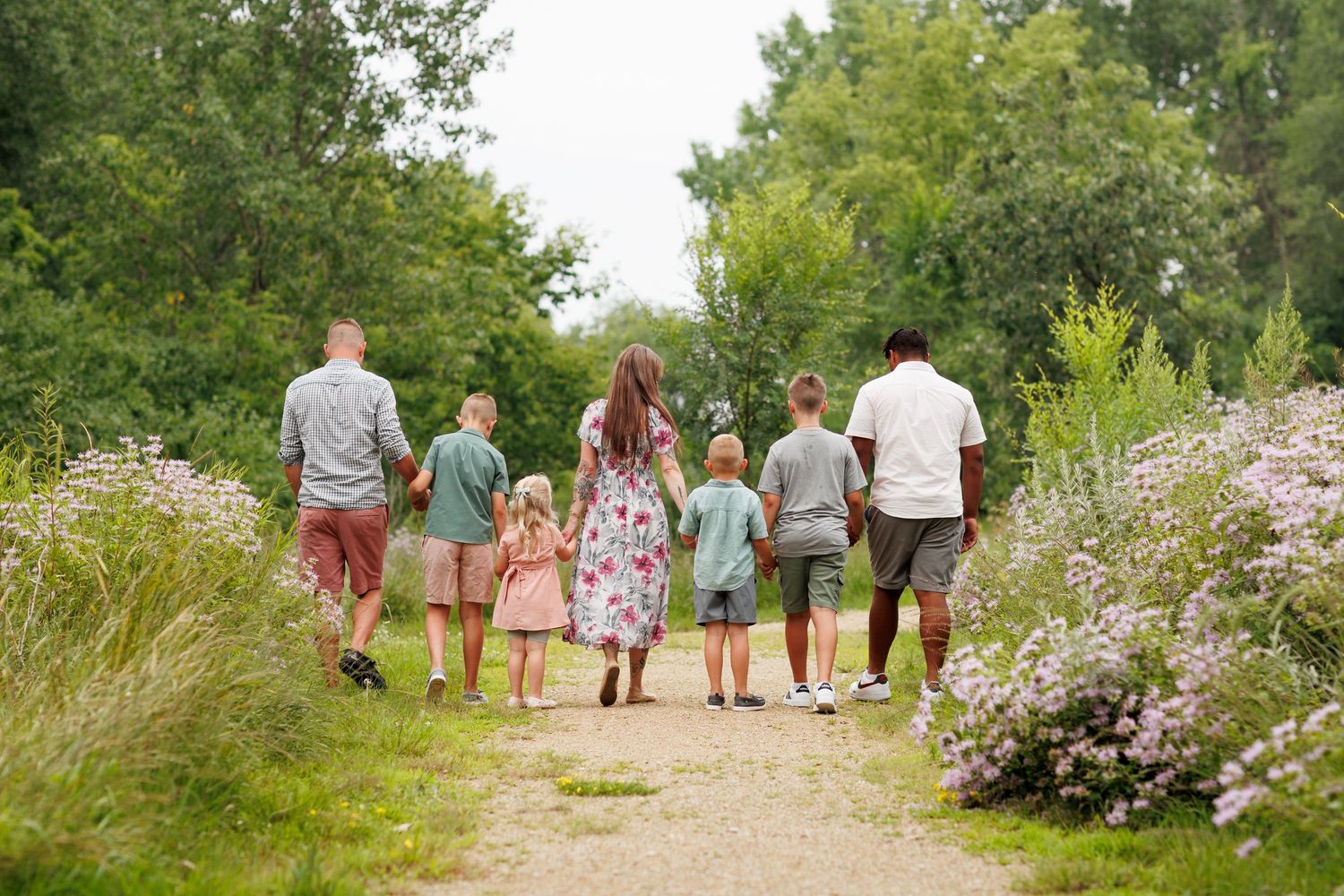 Family walking together on a tree-lined path during an outdoor photo session.