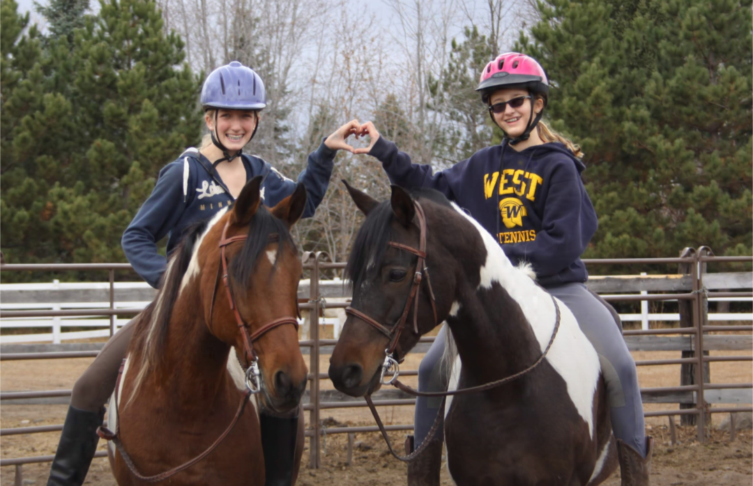 Riders practicing horseback riding in an outdoor arena during winter.