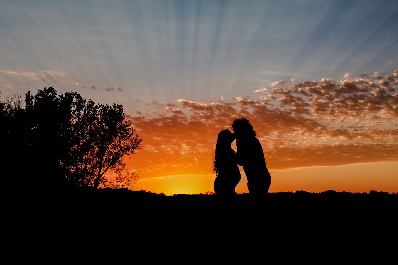Silhouette of couple against dramatic orange sunset sky.